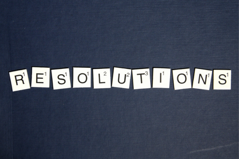 scrabble letters spelling 'resolutions' on dark grey background