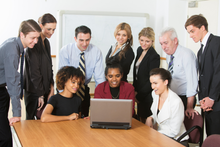 10 staff members looking at one laptop