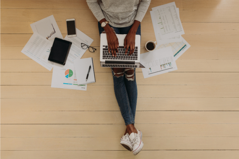 bird's view of a person working from home on a laptop, with a smarphone and tablet lying next to them