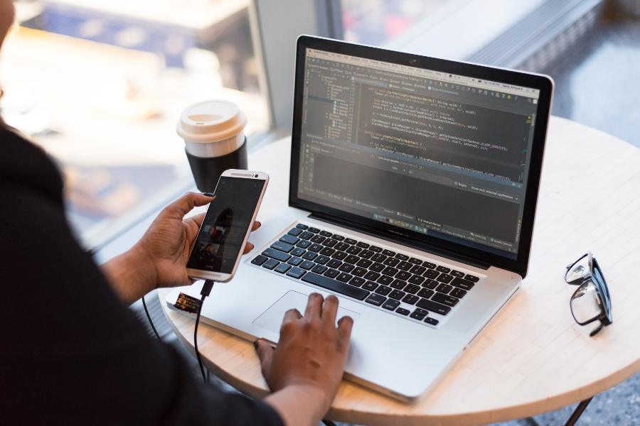 a person holding a phone in front of their laptop