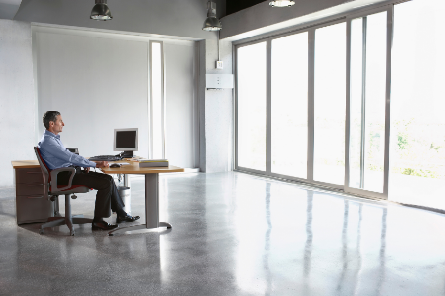 Man sitting alone in a big bright office, looking out of the window