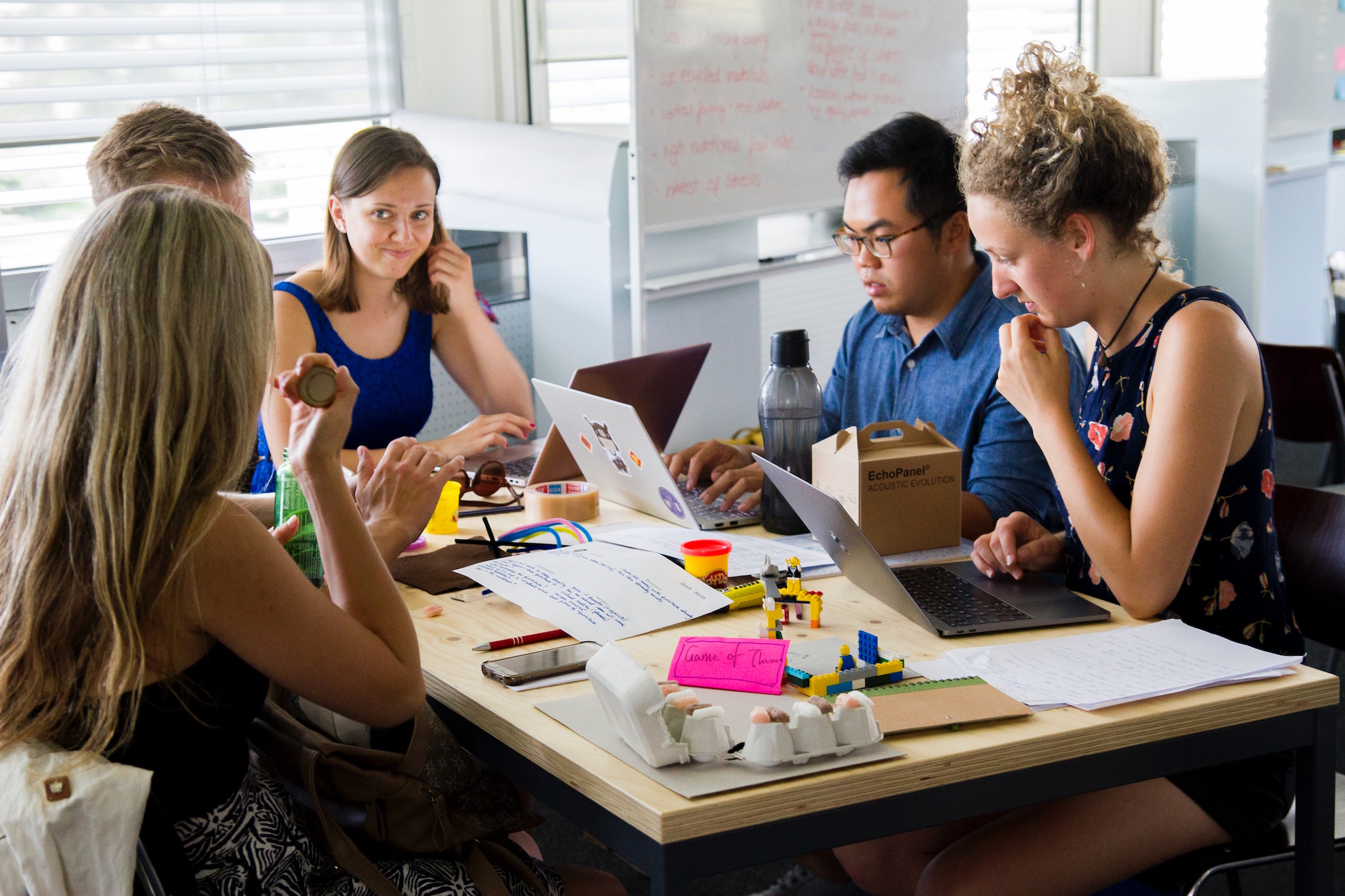 A group of small business owners sitting around a table holding paper and looking at laptops.