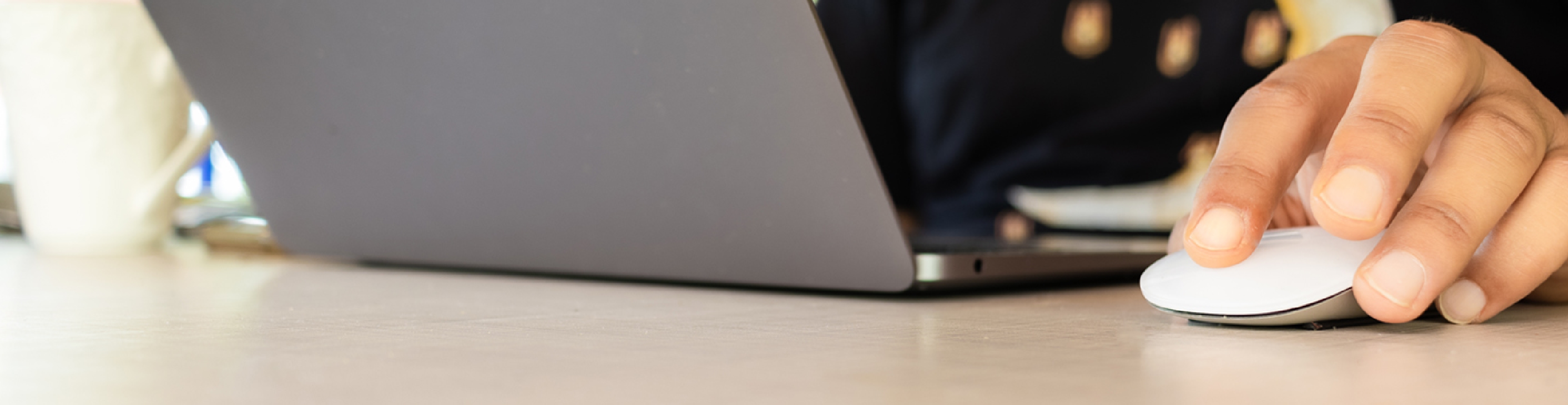 Close up of hands working at a laptop with a mouse